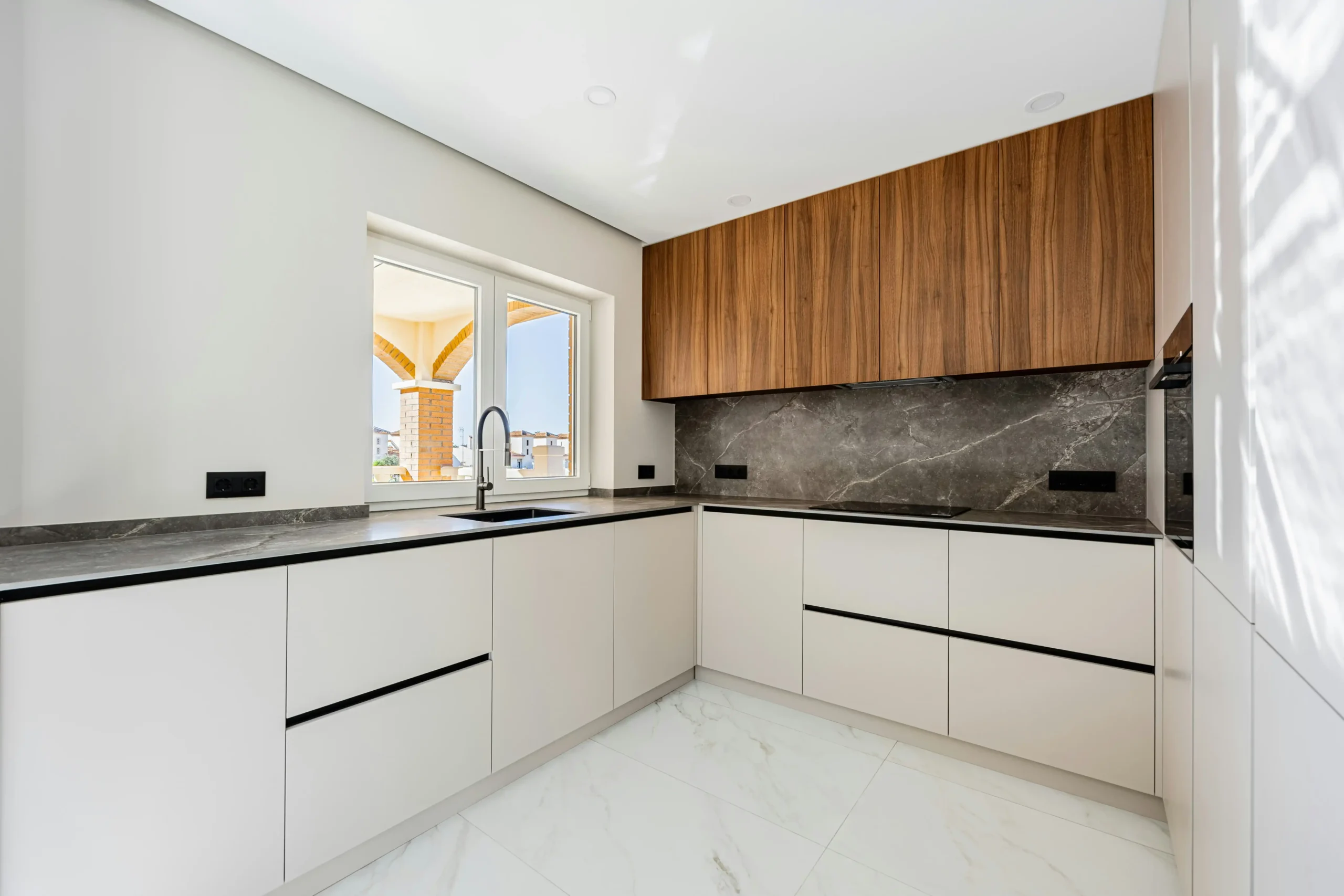 L-shape kitchen renovation in Dubai with white cabinetry and warm wood accents.
