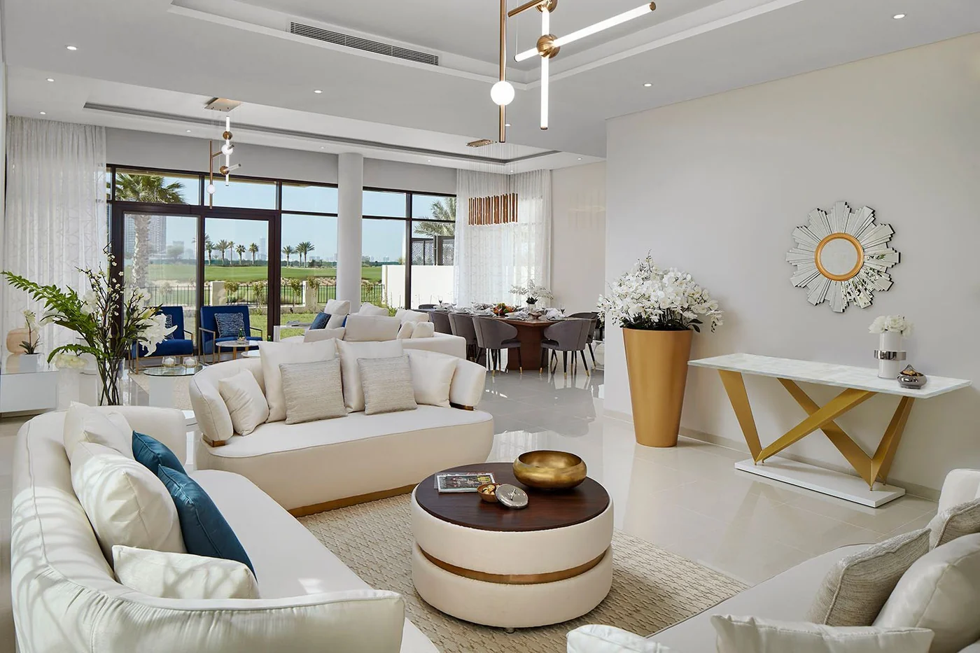 Modern villa living and dining area showing a cohesive neutral and gold material palette with statement lighting