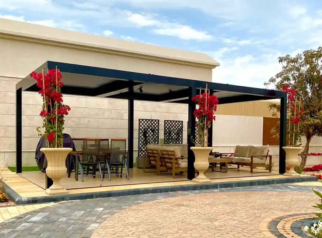 Black powder-coated aluminium pergola shading a villa garden seating area