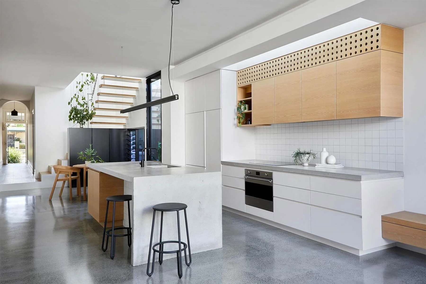 Modern kitchen with custom joinery cabinets, island seating, and warm wood upper units