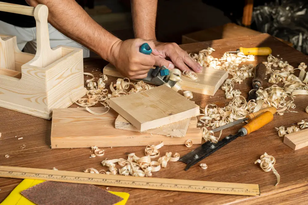 Craftsperson planing wood in a joinery workshop for custom cabinets and storage units