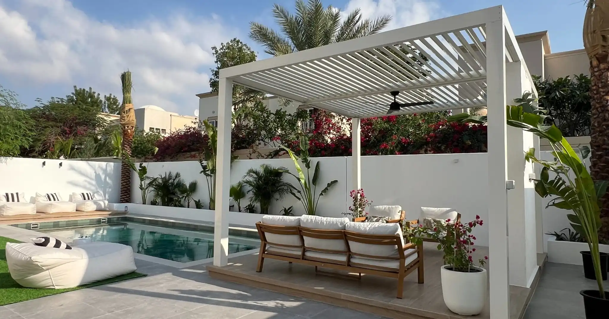 Modern white aluminium pergola shading a poolside seating area in a Dubai villa garden