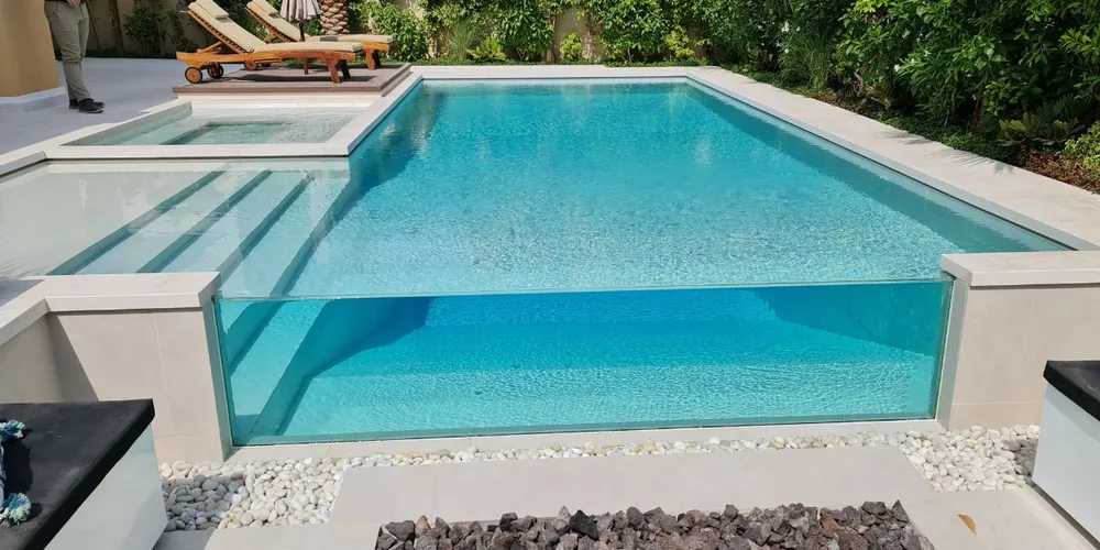Pool with glass wall feature showing clear viewing panel and modern backyard layout
