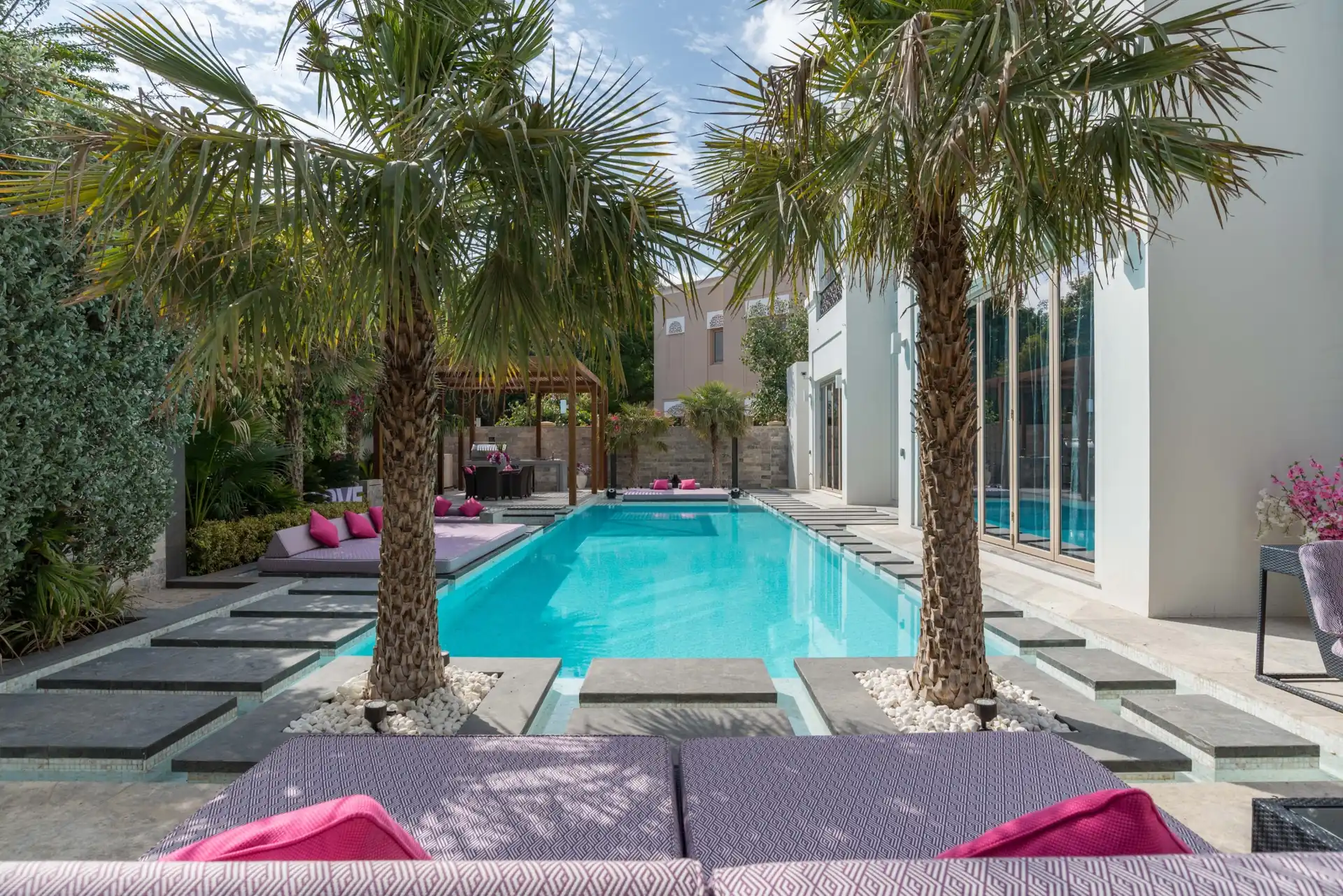Swimming pool design in Dubai villa backyard with palm trees and stone deck